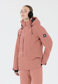 Veste rose imperméable avec capuche, fermeture éclair sur le devant et cordons ajustables. Présente des accents noirs et un logo sur la manche gauche.