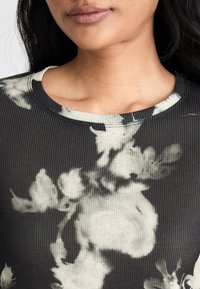 Schwarz geripptes Oberteil mit einem floralen Muster in Grau und Weiß. Verfügt über einen runden Halsausschnitt und eine strukturierte Stoffdetail.