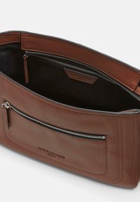 Brown leather bag with a zippered main compartment and an exterior zipped pocket. Smooth texture, clean lines, and a logo tag inside.