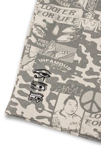 Katoenen stof met een camouflagepatroon in grijs, met verschillende grafische prints en borduurontwerpen, waaronder een paar ogen en tekstfragmenten.