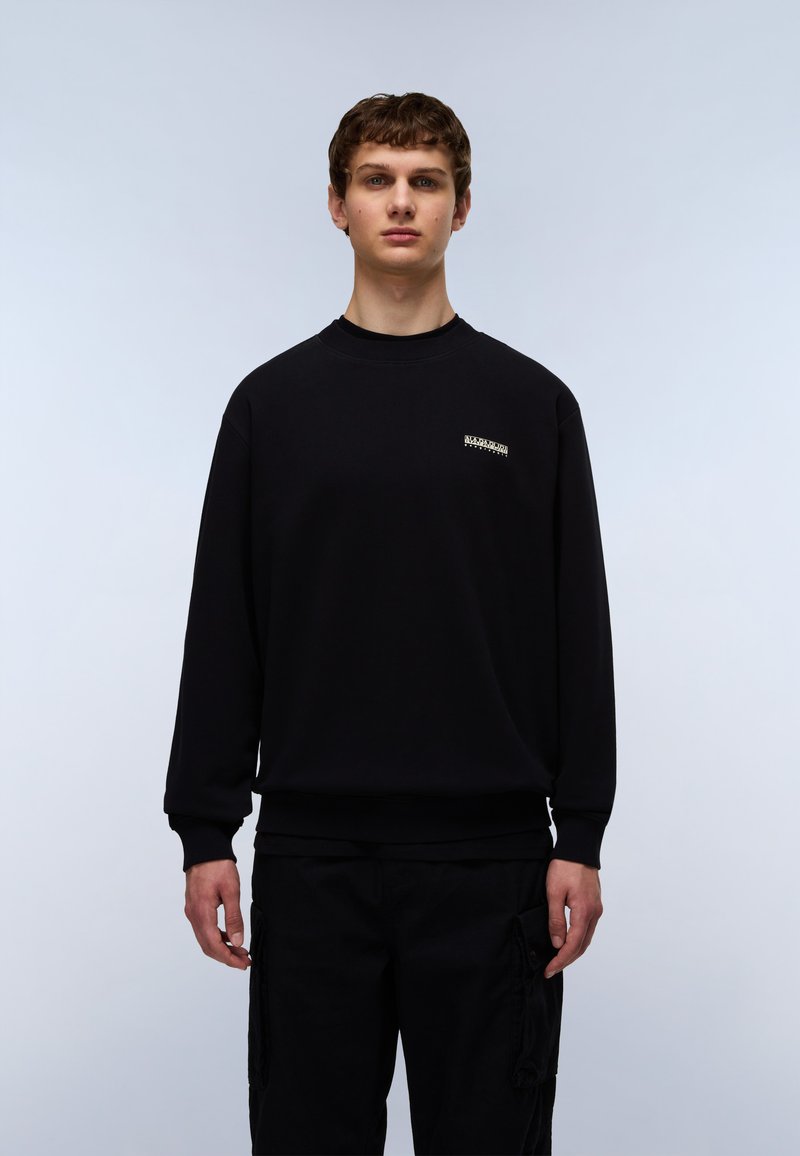 Sort sweatshirt lavet af bomuld, med ribbet halsudskæring og manchetter, samt en lille logo detalje på brystet. Kombineret med sorte cargo-bukser.