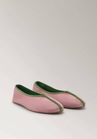 Pair of pink slip-on shoes with green trim and split toe design, displayed on a neutral background.