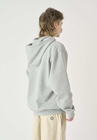 Grauer Kapuzenpullover aus weichem Stoff, mit lockerer Passform, gerippten Bündchen und einem schlichten Design ohne Verzierungen.
