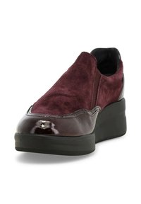 Scarpa scivolosa color bordeaux con tomaia in camoscio, punta in vernice lucida e suola piatta in gomma. Presenta pannelli laterali elastici per una facile calzata.