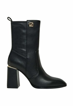 Stivale alla caviglia in pelle nera con punta appuntita, tacco quadrato spesso e dettaglio hardware dorato discreto. Texture liscia e design elegante.