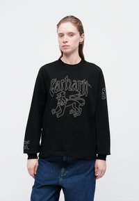 Crna dukserica dugih rukava s grafičkim dizajnom koji prikazuje lava, tekst "Carhartt" u srebrnom vezu i rebraste manžete.