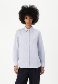 Svetlo modra in bela prugasta srajca s kragnico, dolgimi rokavi in majhnim logotipom na prsih. Mehka tkanina in sproščen kroj.