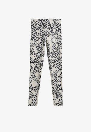 Leggings de couleur crème avec un motif floral abstrait noir, dotés d'une taille élastique et d'une silhouette ajustée et mince.