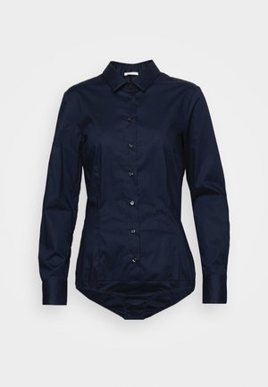 Marineblauw longsleeve button-up romper met kraag en aangesloten taille, weergegeven op een vlakke, neutrale grijze achtergrond.