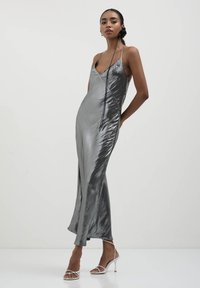 Silbernes Satin-Slip-Kleid mit dünnen Trägern, einer taillierten Silhouette und einem seitlichen Schlitz, das eine glatte, reflektierende Textur präsentiert.