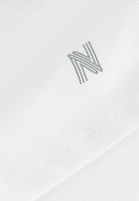 Biały materiał z subtelnym, wytłoczonym logo "N" w jasnoszarym kolorze. Gładka tekstura z starannym ściegiem wzdłuż krawędzi.