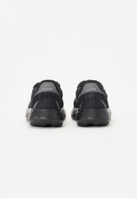Baskets noires de sport avec une tige en mesh et en daim, remarquables pour leur design bicolore avec des accents gris et une semelle en caoutchouc texturée.