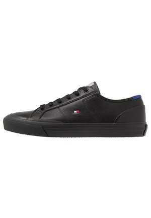 Czarny niski skórzany sneaker z czarnymi sznurówkami, płaską gumową podeszwą, małym czerwono-biało-niebieskim logo po boku oraz niebieskim paskiem na pięcie.