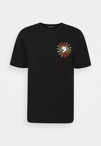 Camiseta de algodón negra con escote redondo. Presenta un gráfico espiral colorido con el texto "SCOTCH&SODA" en el lado izquierdo del pecho. Mangas cortas.