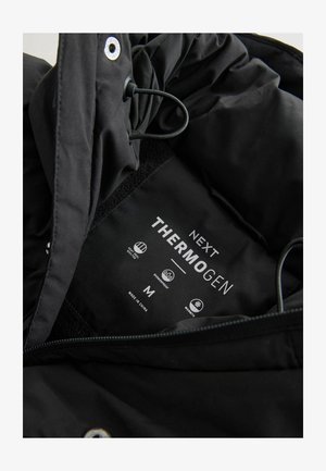 Black Thermogen jacket interior with adjustable drawstring, features care labels, and waterproof and warmth icons. Size M.