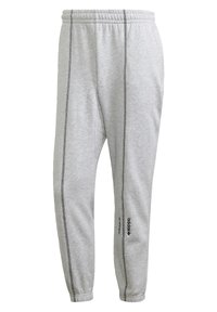 Šedé tepláky z měkké látky s elastickým pasem, zúženými nohavicemi, černým bočním švem a logem na levé noze.