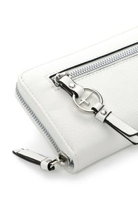 Portefeuille en cuir blanc avec détails de fermeture éclair en argent et un charm métallique circulaire attaché à une lanière en cuir sur la poche avant.