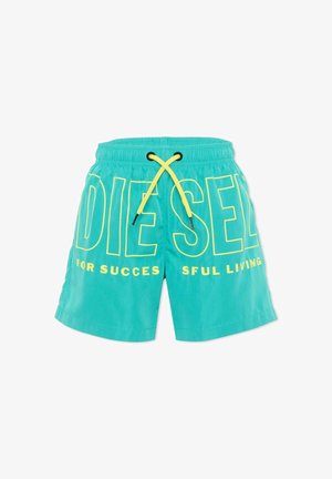 Bañador corto turquesa con cordón amarillo y gran texto del logo Diesel en amarillo, incluyendo la frase parcial "FOR SUCCESSFUL LIVING" en la parte delantera.