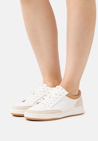 Sneaker bianche in pelle con dettagli in suede beige, punta rotonda e design con lacci. Presentano un tacco marrone chiaro e una suola in gomma marrone chiaro.