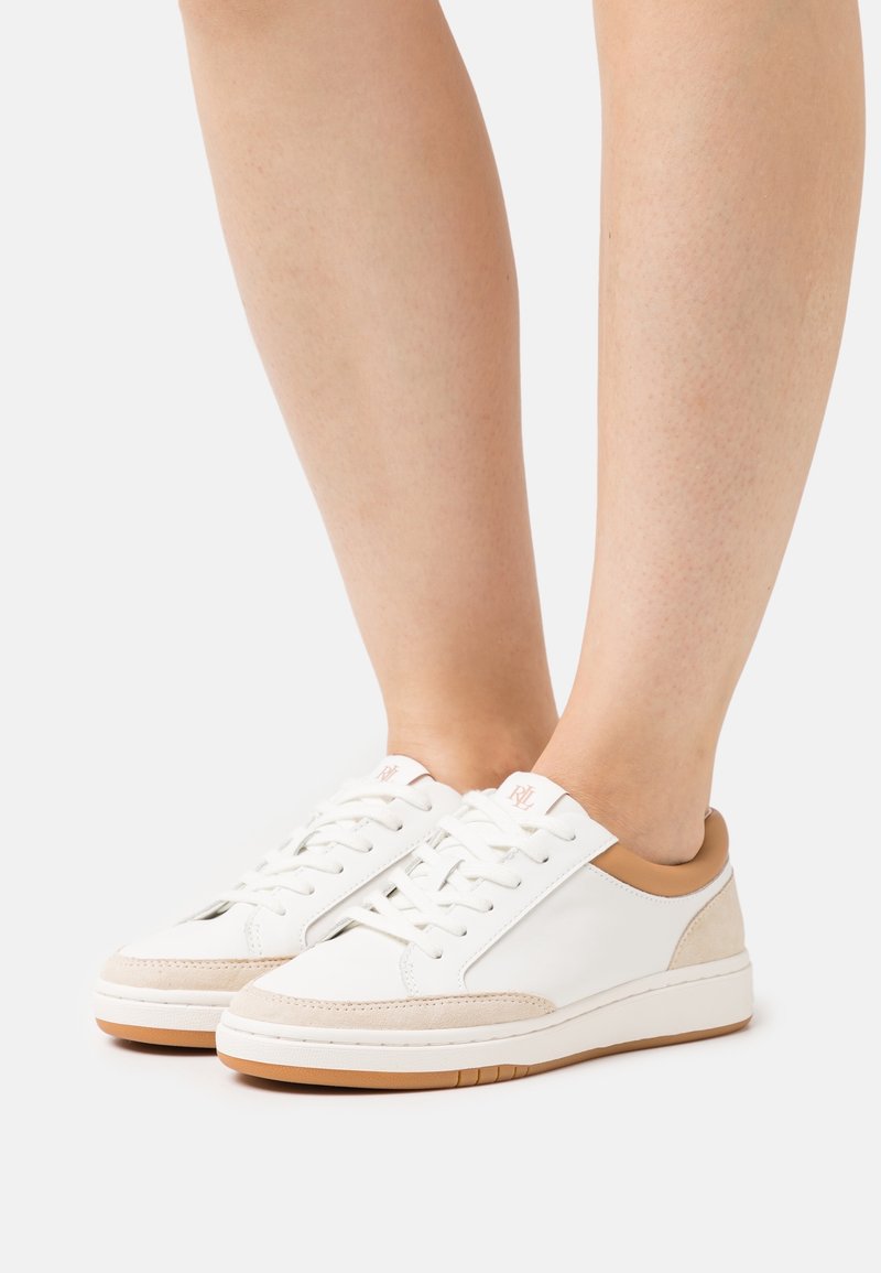 Sneaker bianche in pelle con dettagli in suede beige, punta rotonda e design con lacci. Presentano un tacco marrone chiaro e una suola in gomma marrone chiaro.