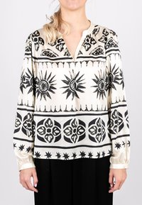 Seidenbluse mit einem cremefarbenen Hintergrund, versehen mit auffälligen schwarzen Sonnen- und Blumenmustern, einem V-Ausschnitt und langen Ärmeln mit gerafften Manschetten.