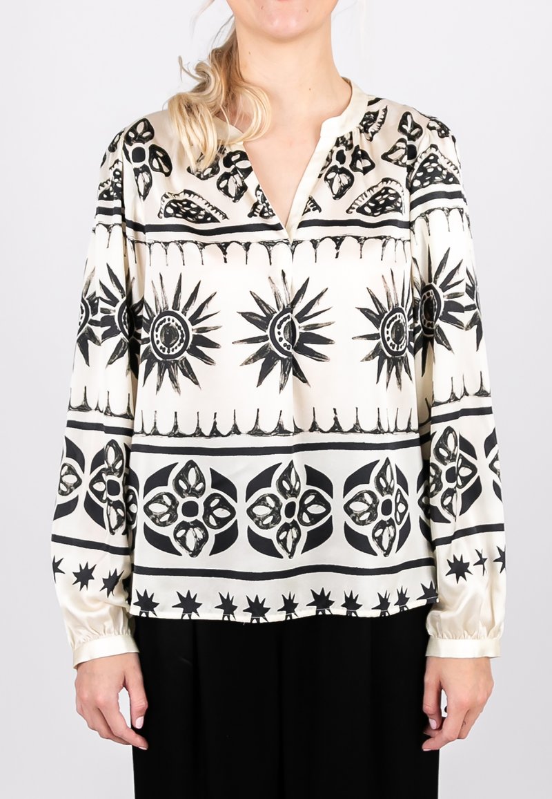 Seidenbluse mit einem cremefarbenen Hintergrund, versehen mit auffälligen schwarzen Sonnen- und Blumenmustern, einem V-Ausschnitt und langen Ärmeln mit gerafften Manschetten.