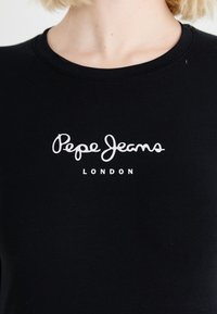 Black round-neck shirt with white "Pepe Jeans London" logo text on the chest, worn by a person with light skin and blonde hair.