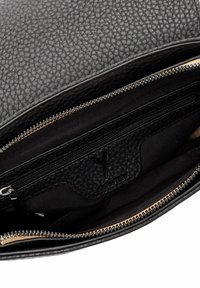 Black leather handbag interior with a textured surface, featuring a zippered compartment and a fabric lining. Gold zipper detail visible.