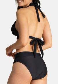 Ensemble bikini noir composé d'un haut à col licou avec liens et d'un bas taille haute. Texture de tissu lisse avec un design minimaliste.
