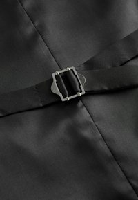 Black fabric with a smooth texture. Features a metal buckle fastening and a stitched strap, highlighting a sleek, minimalist design.