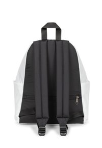 Mochila en blanco y negro, con forma redondeada, correas acolchadas, bolsillo con cremallera y bolsillos laterales de malla para almacenamiento extra.