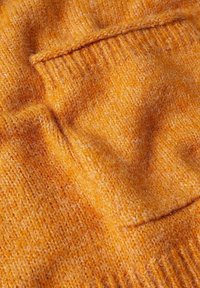 Tissu de pull en tricot orange, avec une texture douce, des fibres visibles et une poche. Le design est chaleureux et accueillant avec une apparence douillette.