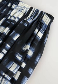 Zwarte stoffen rok met plooien, met een blauw en wit geometrisch patroon. Elastische taille en een gladde textuur.