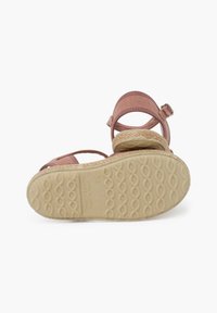 Sandalias de tela rosa con puntera abierta, correas para el tobillo y suela beige texturizada con un patrón ondulado. Hebilla ajustable para un calce seguro.
