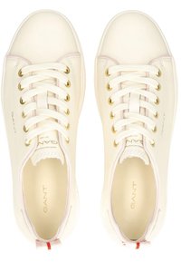 Sneakers bianchi in pelle con occhielli dorati, lacci piatti e un sottile accento rosa. Presentano un logo sul lato e un tab sul tallone rosso e bianco.