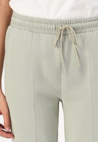 Lichtgroene sweatpants van zacht materiaal, met een elastische tailleband en een trekkoord, en zijnaaddetails.