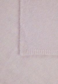 Tissu en cachemire rose clair avec une texture douce. Motifs de tissage visibles, une bordure présente une finition effilochée pour plus de détail.