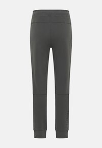 Dunkelgraue Sweatpants mit einem gerippten Bund, schmal zulaufenden Beinen und Nähdetails. Logo auf dem Unterschenkel gedruckt, glatte Stofftextur.