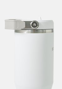 Tasse de voyage en acier inoxydable blanc à double paroi, avec une bande argentée, un couvercle gris avec poignée, et une finition mate lisse.