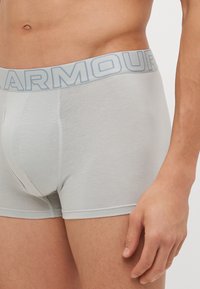 Grå boxershorts laget av myk bomullsblanding, med et lys blått elastisk liv med "ARMOUR"-logo, designet for komfort og støtte.