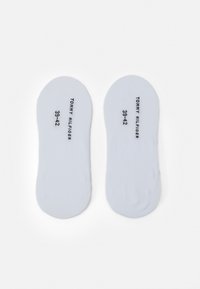 Hvite såler med en glatt tekstur, merket med "TOMMY HILFIGER 39-42." Rund form, designet for komfort, uten synlige mønstre.