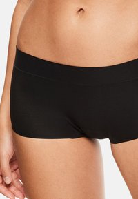 Shorts noirs en forme de boyshorts fabriqués dans un tissu doux et extensible avec une ceinture sans couture, offrant un ajustement lisse et confortable.
