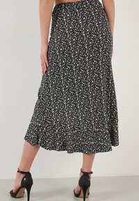 Fustă midi neagră cu un model floral, cu un tiv cu volane și talie elastică, având un mic model cu flori albe și un material fluid, ușor.