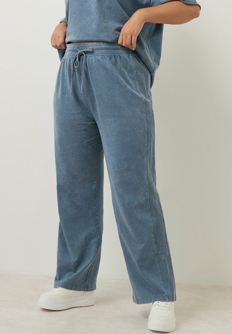 Ljusblå, vida sweatpants gjorda av mjukt material. Har ett elastiskt midjeband med dragsko och sid sömmar. Matchas med vita sneakers.