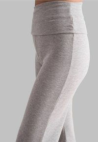 Szare prążkowane legginsy z szerokim pasem, z małym srebrnym akcentem logo. Materiał wydaje się być miękki i rozciągliwy, zaprojektowany z myślą o komforcie.
