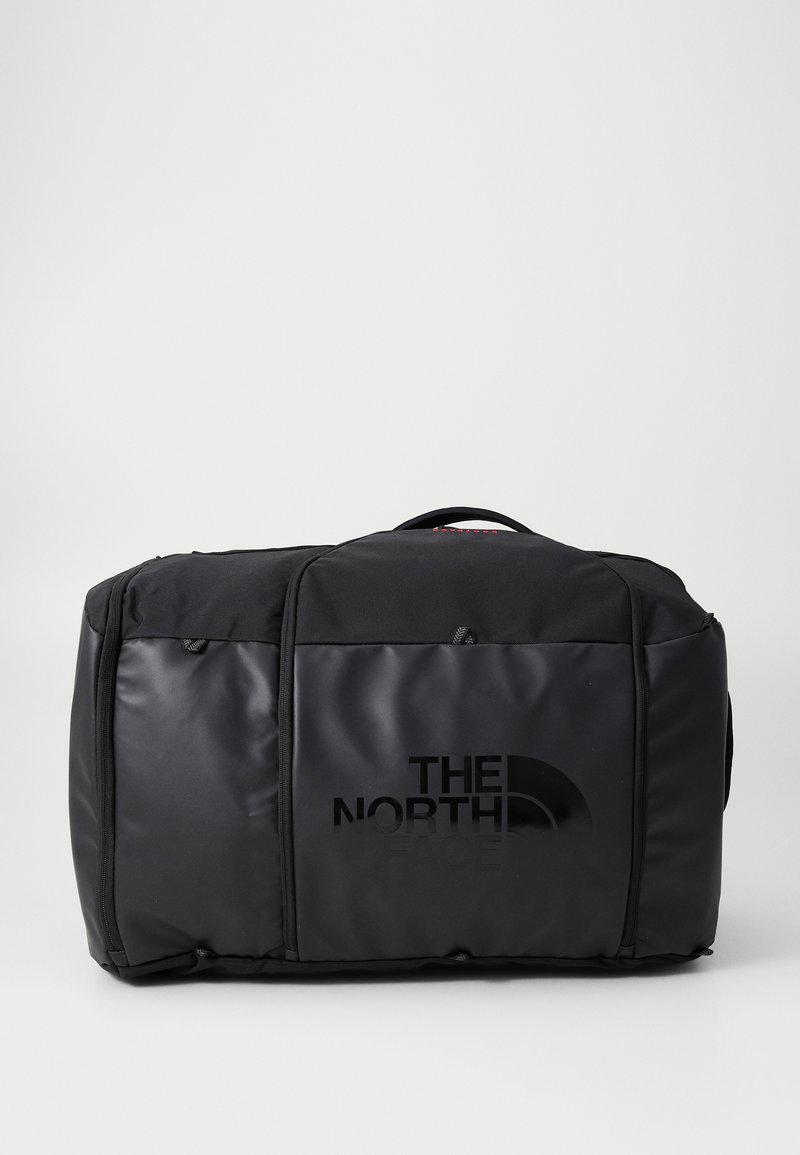 Svart duffelbag laget av slitesterkt materiale, med et stilrent design, frontlommer med glidelås og "The North Face"-logoen tydelig utstilt.
