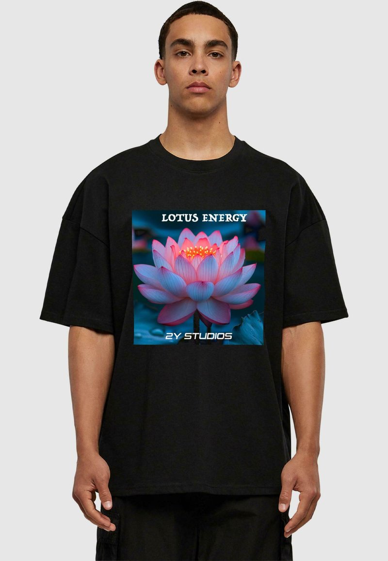 Černé oversized tričko s barevným grafikou lotosu, s nápisy "LOTUS ENERGY" a "2Y STUDIOS" v bílém, které jsou výrazně zobrazeny.