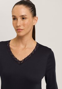 Laadukkaasta pehmeästä kankaasta valmistettu laivastonsininen V-pääntie toppi, jossa on monimutkaista pitsikoristelua kaula-aukossa, pitkät hihat ja vartalonmyötäinen malli.