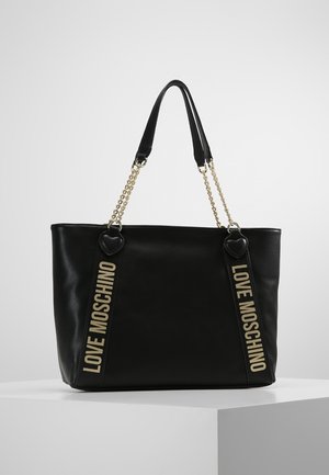 Sac cabas en cuir noir avec chaîne dorée et anses noires, avec "LOVE MOSCHINO" imprimé verticalement en beige sur les côtés avant.