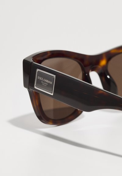 Tortoiseshell sunglasses with brown tinted lenses, featuring a rectangular shape and a silver logo plate on the temple.
